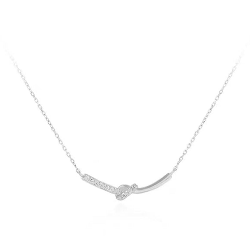 Fein gebogener Anhänger mit Pavé-Zirkonia und sanftem Knoten – ein leiser Glanz, der jeden Look modern abrundet. Ideal solo getragen oder im Layering.